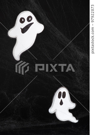 Two merry ghosts with faces fly and smile on a black background with a web. Halloween card, a place for text 97922873