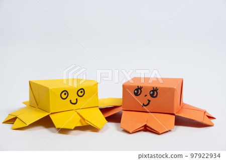 Two cute yellow and orange origami octopuses on a white background, paper animal figurines 97922934