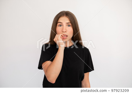 Portrait of frightened young woman biting nails 97923209