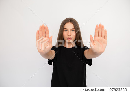 Portrait of serious young woman making stop gesture Portrait of serious young woman making stop gesture 97923233