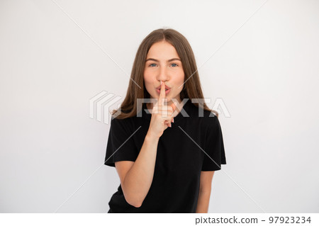 Portrait of flirty young woman making silence gesture Portrait of flirty young woman making silence gesture 97923234