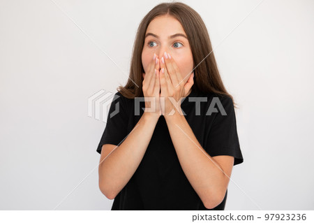 Portrait of frightened young woman covering mouth with hands Portrait of frightened young woman covering mouth with hands 97923236