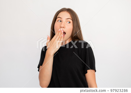 Portrait of flirty young woman covering mouth with hand 97923286