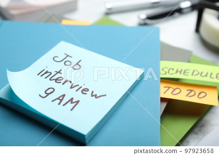 Reminder note about job interview and stationery on table, closeup 97923658
