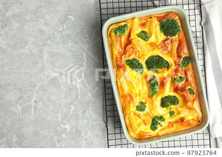 Tasty broccoli casserole in baking dish on cooling rack, top view. Space for text 97923764