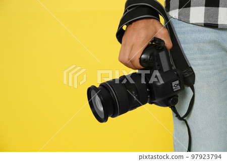 Professional photographer with modern camera on yellow background in studio, closeup. Space for text Professional photographer with modern camera on yellow background in studio, closeup. Space for text 97923794