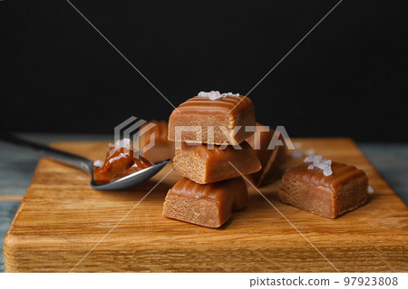 Delicious salted caramel on wooden board, closeup 97923808