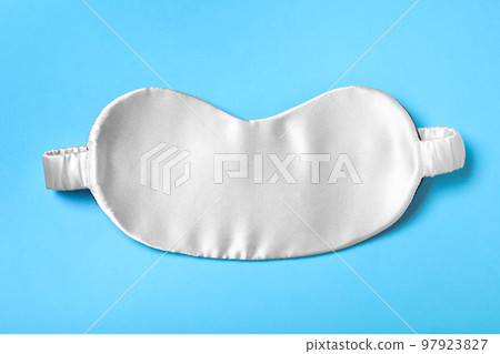 White sleeping mask on light blue background, top view. Bedtime accessory 97923827