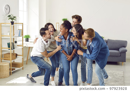 Happy young people laughing at a funny joke their friend has told at a party at home Happy young people laughing at a funny joke their friend has told at a party at home 97923928