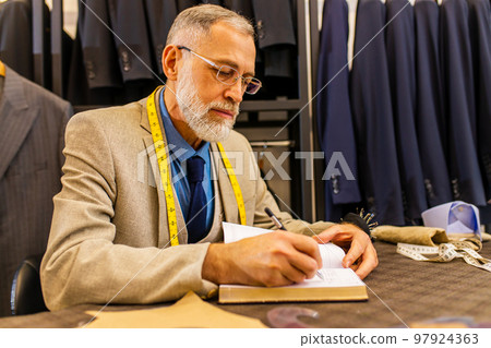 elderly good looking man in stylish and rich suit owner of atelier studio busy with work 97924363