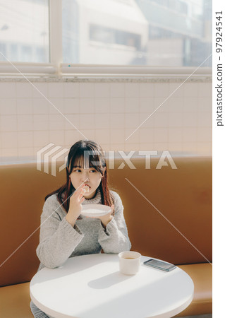 女大學生在咖啡館吃甜甜圈 女大學生在咖啡館吃甜甜圈 97924541