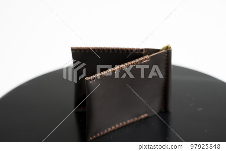Handmade brown men's money clip handmade leather wallet with a two pockets on a black table. Selective focus, copy space, Close up. 97925848