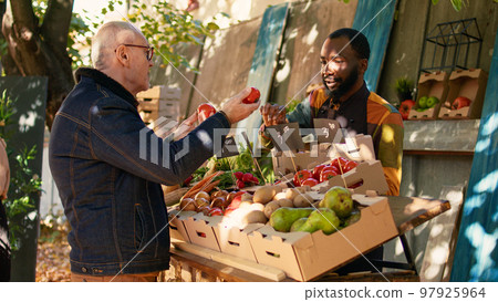 Group of diverse people talking about farmers market products on stand, looking at healthy products on counter. Elderly man and local stall holder choosing organic fruits and veggies. Group of diverse people talking about farmers market products on stand, looking at healthy products on counter. Elderly man and local stall holder choosing organic fruits and veggies. 97925964
