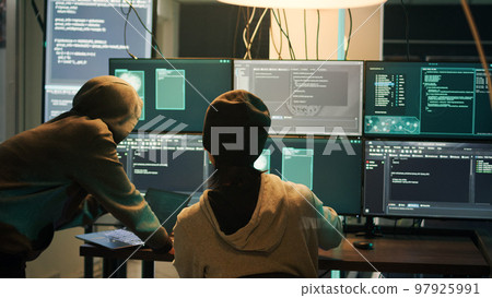 Diverse criminals hacking security server with malware, working on cyberbullying late at night. Hackers phishing for information, stealing valuable data, breaking firewall encryption. 97925991