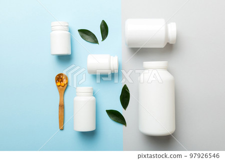supplement pills with medicine bottle health care and medical top view. Vitamin tablets. Top view mockup bottle for pills and vitamins with green leaves, natural organic bio supplement, copy space 97926546