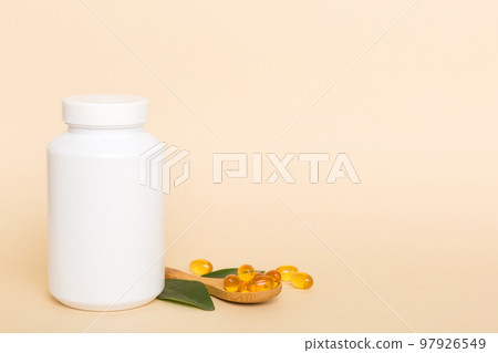 Omega-3 capsules lie in white bottle on a table with green leaves background. Fish oil tablets. Biologically active additives. omega 6, omega 9, vitamin A, E, D, vitamin D3 top view with copy space 97926549
