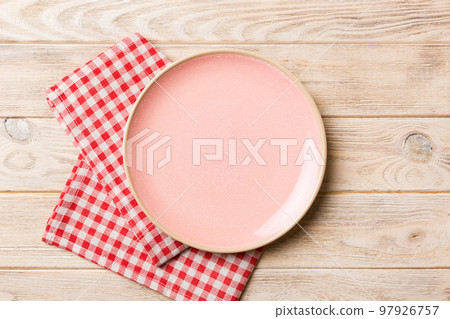 Top view on colored background empty round pink plate on tablecloth for food. Empty dish on napkin with space for your design Top view on colored background empty round pink plate on tablecloth for food. Empty dish on napkin with space for your design 97926757