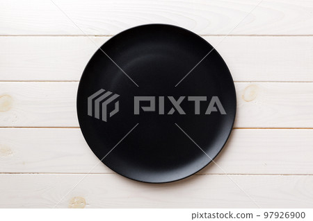 Top view of black plate on wooden background. Empty space for your design Top view of black plate on wooden background. Empty space for your design 97926900