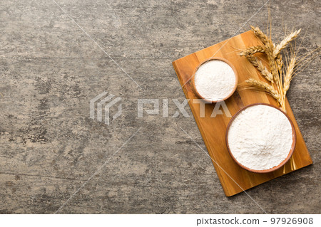 Flat lay of Wheat flour in wooden bowl with wheat spikelets on colored background. world wheat crisis Flat lay of Wheat flour in wooden bowl with wheat spikelets on colored background. world wheat crisis 97926908