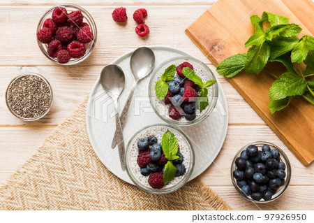 Healthy breakfast or morning with chia seeds vanilla pudding raspberry and blueberry berries on table background, vegetarian food, diet and health concept. Chia pudding with raspberry and blueberry 97926950