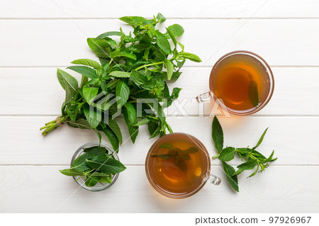 Cup of mint tea on table background. Green tea with fresh mint top view with copy space Cup of mint tea on table background. Green tea with fresh mint top view with copy space 97926967