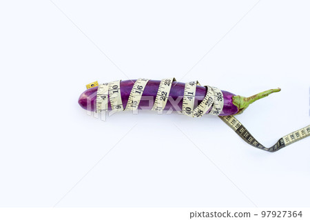 Long purple eggplant wrapped in measuring tape on white background. 97927364
