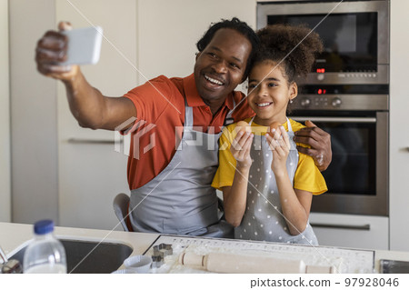 Family Fun. Black Father And Daughter Taking Selfie On Smartphone In Kitchen Family Fun. Black Father And Daughter Taking Selfie On Smartphone In Kitchen 97928046