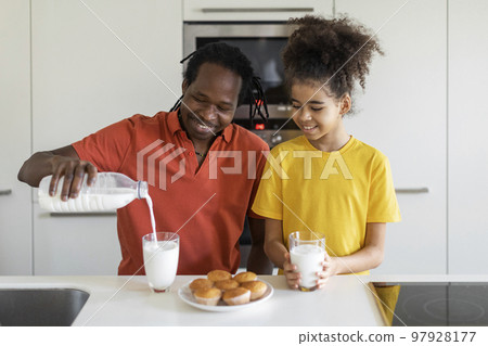 African American Father And His Preteen Daughter Having Snacks In Kitchen 97928177