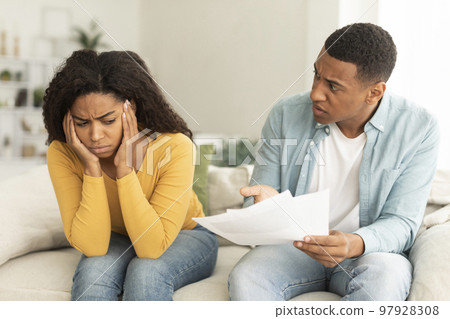 Angry sad millennial african american man with papers swearing woman due debts, taxes and bills 97928308