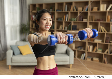Joyful young japanese lady doing domestic training, working out with dumbbells at home, copy space 97928309