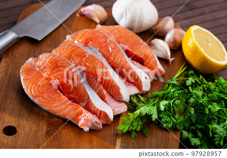 Raw salmon steaks with lemon, parsley, garlic 97928957