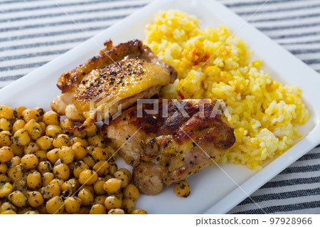 Grilled chicken thighs with garbanzo and yellow rice at plate Grilled chicken thighs with garbanzo and yellow rice at plate 97928966