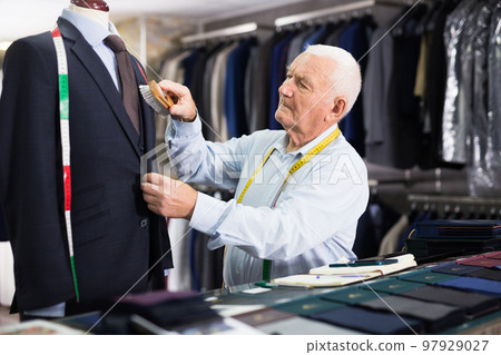 Experienced male tailor brushes a new jacket in workshop 97929027