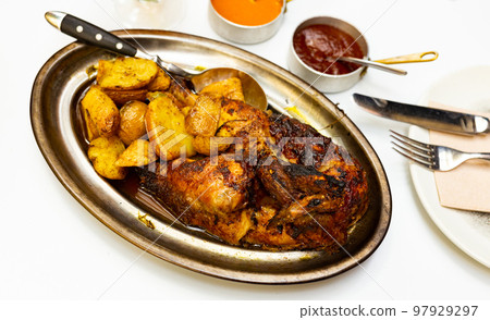 Portion of roasted chicken with potatoes on metal dish 97929297