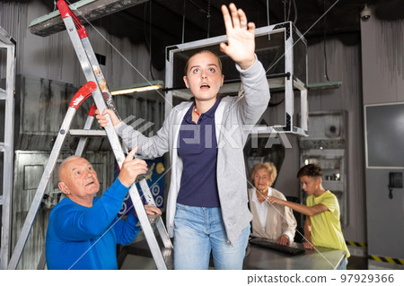 Girl on stepladder in escape room with her family 97929366