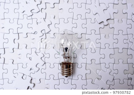 Sparking ideas Background texture of scattered jigsaw puzzles and light bulbs Strategy dark 97930782
