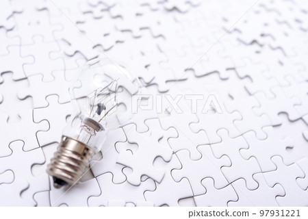 Sparking ideas Background texture of scattered jigsaw puzzles and light bulbs Strategy bright 97931221