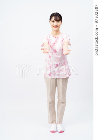 一位年輕的女護士穿著花卉磨砂膏伸出她的手 97932887