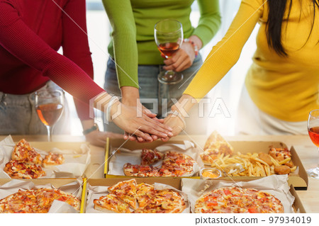 Friends at birthday party clinking glasses with champagne and pizza, enjoying christmas vacation, pizza on the table. Holiday Party event 97934019