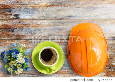 Top view with orange safety helmet,coffee cup and flower on wooden table Top view with orange safety helmet,coffee cup and flower on wooden table 97936577