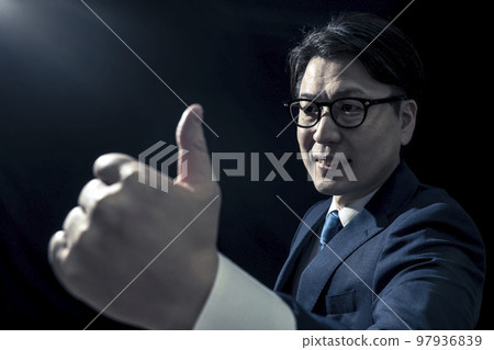 一個穿西裝的男人豎起大拇指表示認可 一個穿西裝的男人豎起大拇指表示認可 97936839