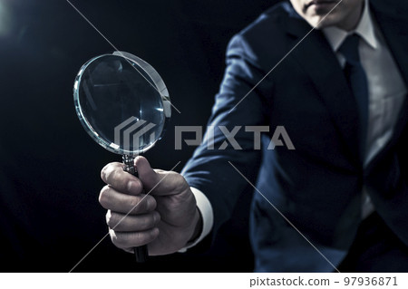 Male business person looking with a magnifying glass 97936871