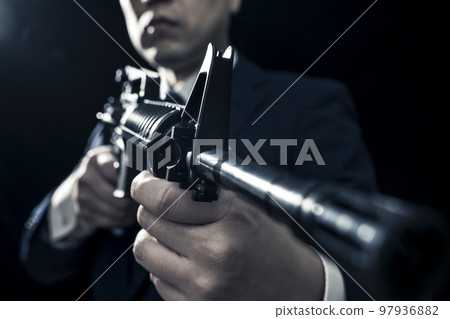 A male business person in a suit holding an automatic rifle A male business person in a suit holding an automatic rifle 97936882