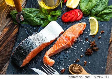 Raw salmon fish fillet with lemon, spinach, spices, olive oil, ready for cooking on slate board 97937917