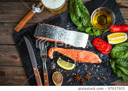 Top down view of raw salmon fish fillet with ingredients on slate cutting board, dark rustic table  97937955