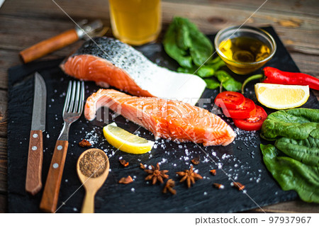 From above view of raw salmon fish fillet with ingredients for cook on slate board. Good food From above view of raw salmon fish fillet with ingredients for cook on slate board. Good food 97937967