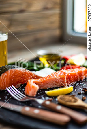Side view of two pieces of raw salmon fillet preparing for cooking on stone cutting board. Good food Side view of two pieces of raw salmon fillet preparing for cooking on stone cutting board. Good food 97937990