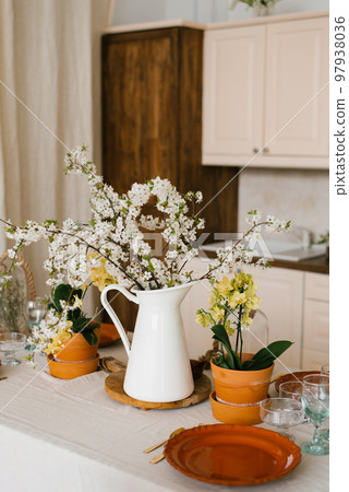 Blooming branches of spring trees in a white vase jug in the Scandinavian-style kitchen decor 97938036