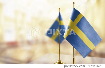Small flags of the Sweden on an abstract blurry background 97940673