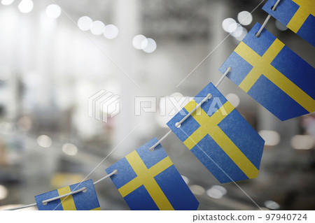 A garland of Sweden national flags on an abstract blurred background 97940724